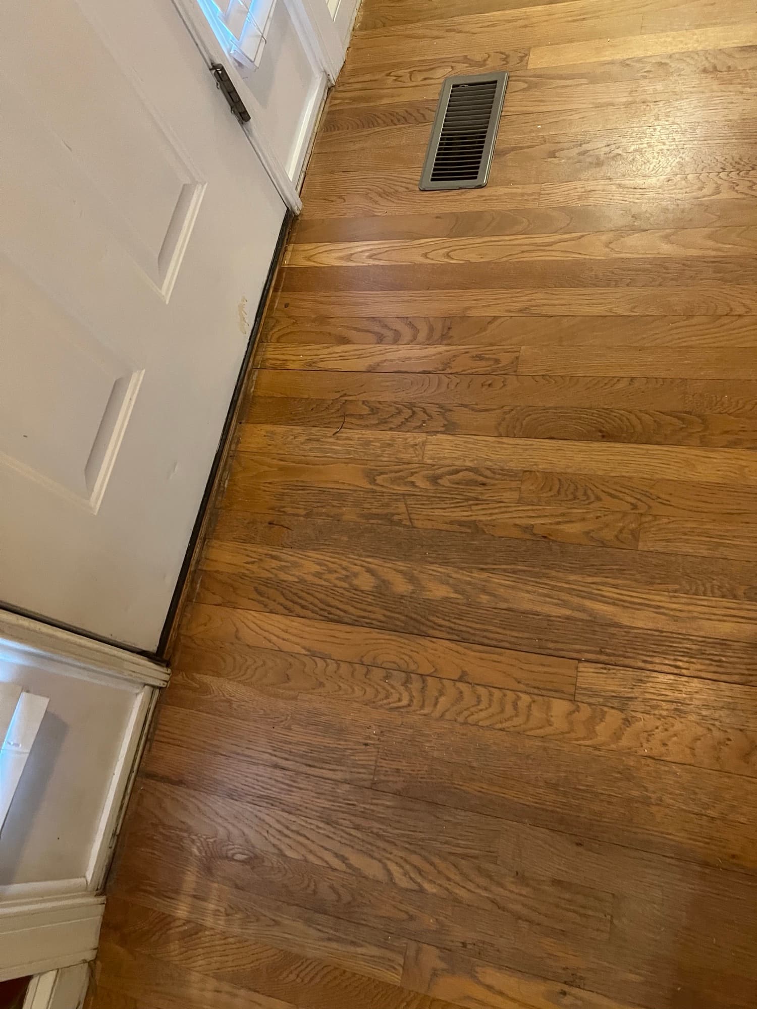 Worn red oak floors near doorway before refinishing in Wilson NC, old oil-based polyurethane heavily ambered and worn through at threshold